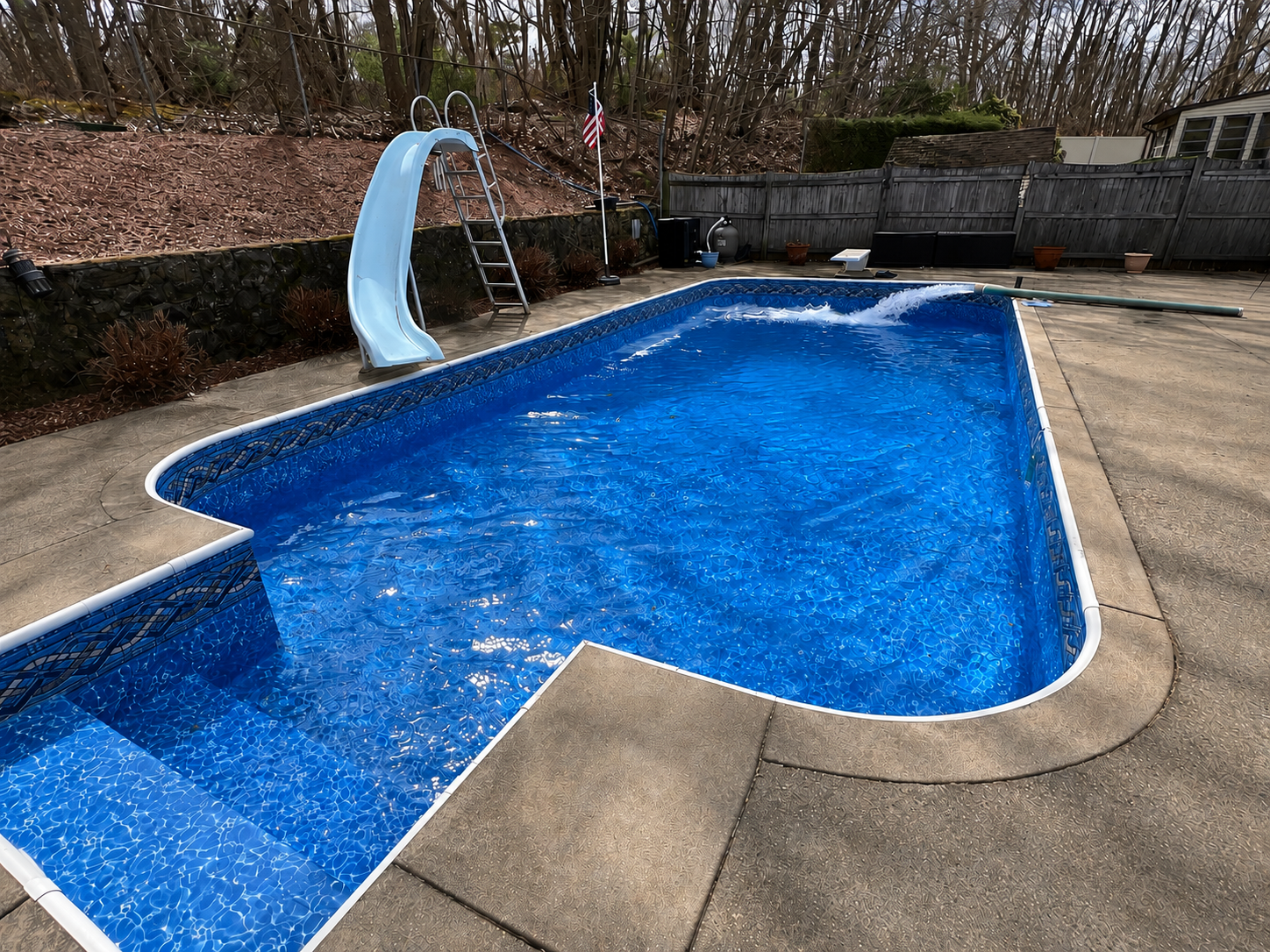 Inground pool after new vinyl liner installation — vibrant blue liner with slide